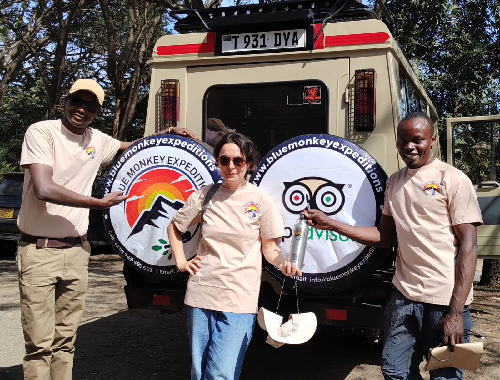 Blue Monkey Expeditions guides with a guest beside their safari vehicle